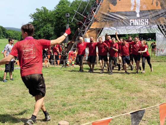 Team im Hintergrund, Frau läuft mir GoPro in der Hand im Vordergrund